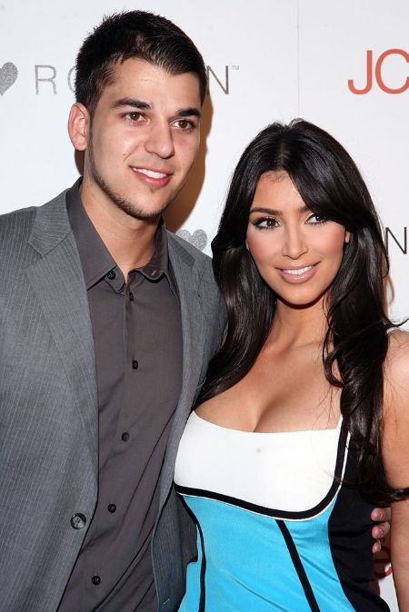 rob wearing a grey suit with kim kardashian in a red carpet 